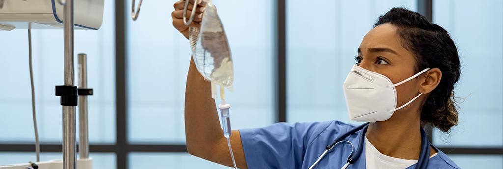 Female nurse checking IV drip in hospital room | CNA Insurance