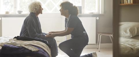 Healthcare worker helping elderly woman l CNA Insurance